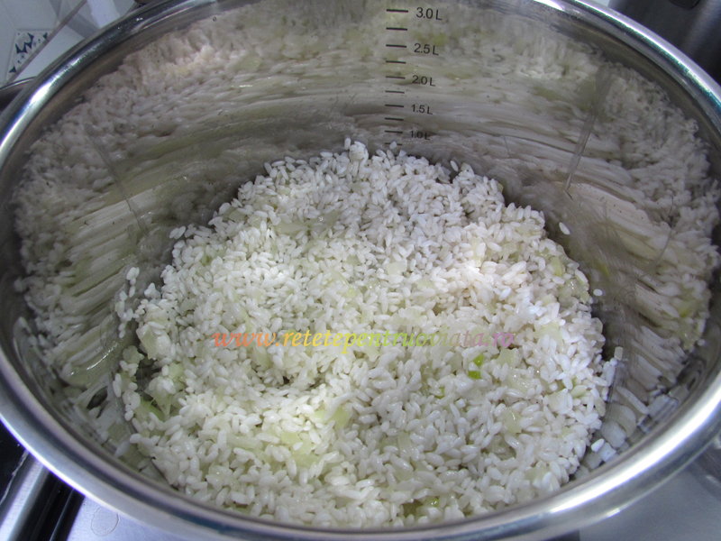 Adaugam orezul si il calim timp de un minut, pana ce boabele de orez se imbiba cu ulei. Astfel, boabele de orez nu se lipesc intre ele la fiert.